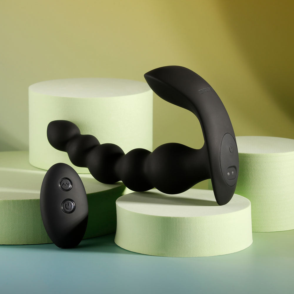 Side view of black vibrating anal beads showing section designed to stimulate between testicles and anus on decorative yellow-greyish background | Flirty Bay, anal plug adult store Australia